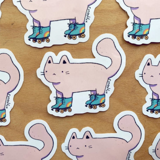 Sticker of a light pink cat in blue roller skates with rainbows on them