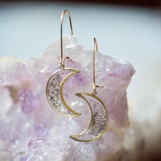 Brass earrings shaped like crescent moons with lightly scattered pyrite sparkling inside