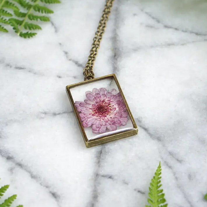 Necklace with a rectangular pendant that showcases an aster flower in resin