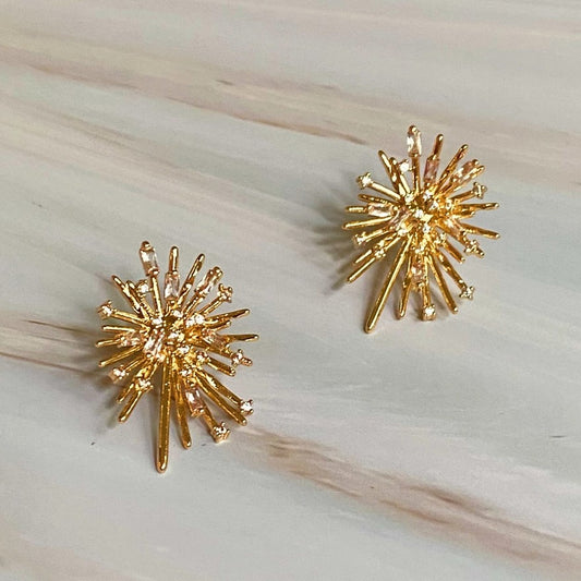 Gold spiky starburst shaped earrings decorated with small white gemstones