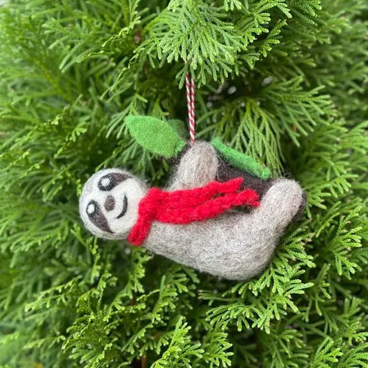 Wool felted ornament shaped like a sloth with a red scarf hanging from a branch