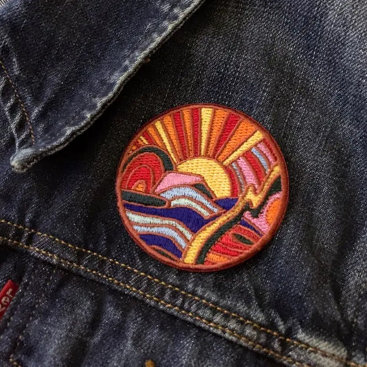 Circular iron-on fabric patches depicting colorful mountains and a sunset
