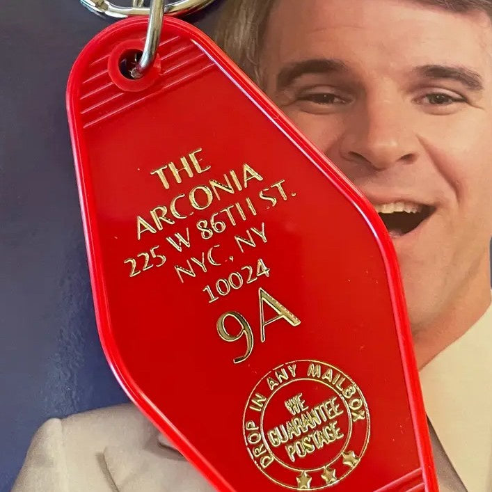 Red keychain tag with gold text that reads "The Arconia" followed by a NYC address
