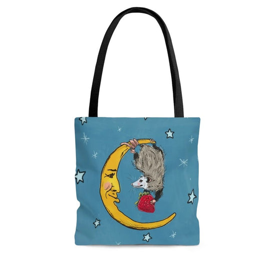 Blue tote bag with stars featuring a moon with a face that has possum hanging off its face while holding a strawberry