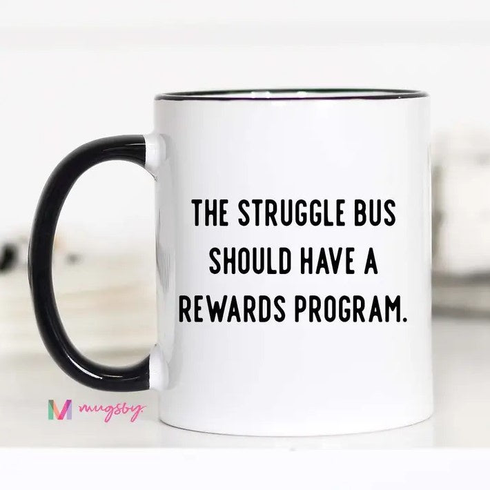 White mug with the words "The struggle bus should have a rewards program." written in black.
