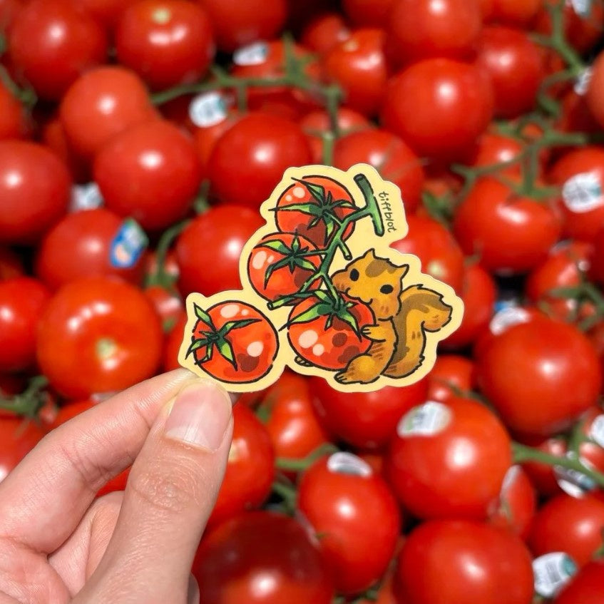 A sticker featuring a mischievously smiling squirrel eating a large tomato off of a tomato vine on a yellow background