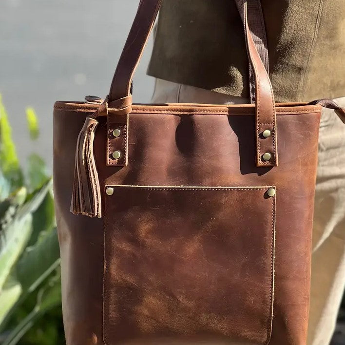A brown leather tote bag with a tassel.