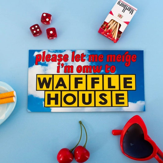 Bumper magnet that reads "please let me merge I'm omw to Waffle House" over a blue cloudy sky background