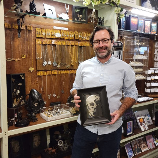 Artist Wes Cribb of Maybe All This holding a framed art print of his design