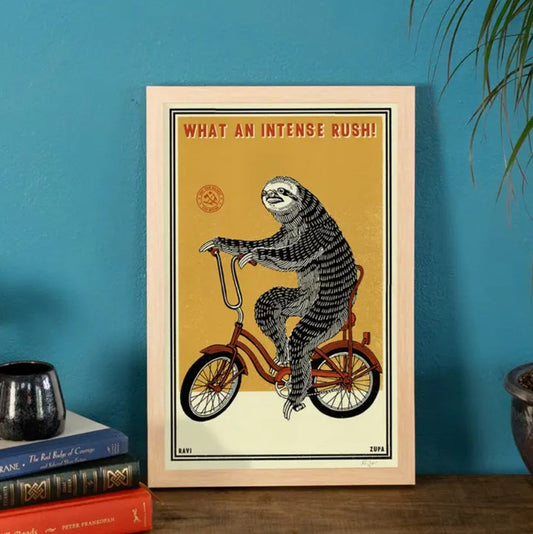 11 by 17 print depicting a sloth riding a bicycle with the caption "What an intense rush!"
