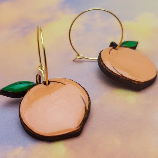 Gold hoop earrings with dangling peaches carved from wood and painted