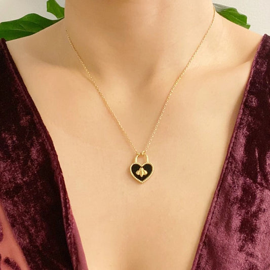 Model wearing a gold and black bee heart lock necklace