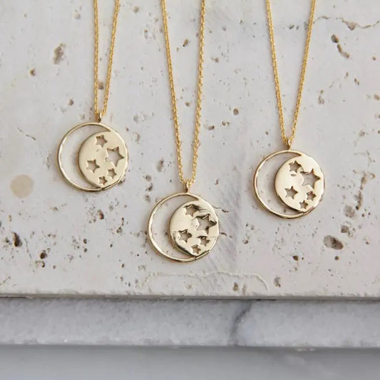 gold circle necklace in the shape of a moon on one side and stars on the other
