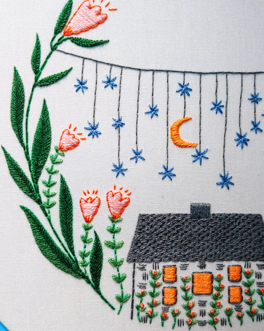 finished embroidery with flowers, stars, and a house