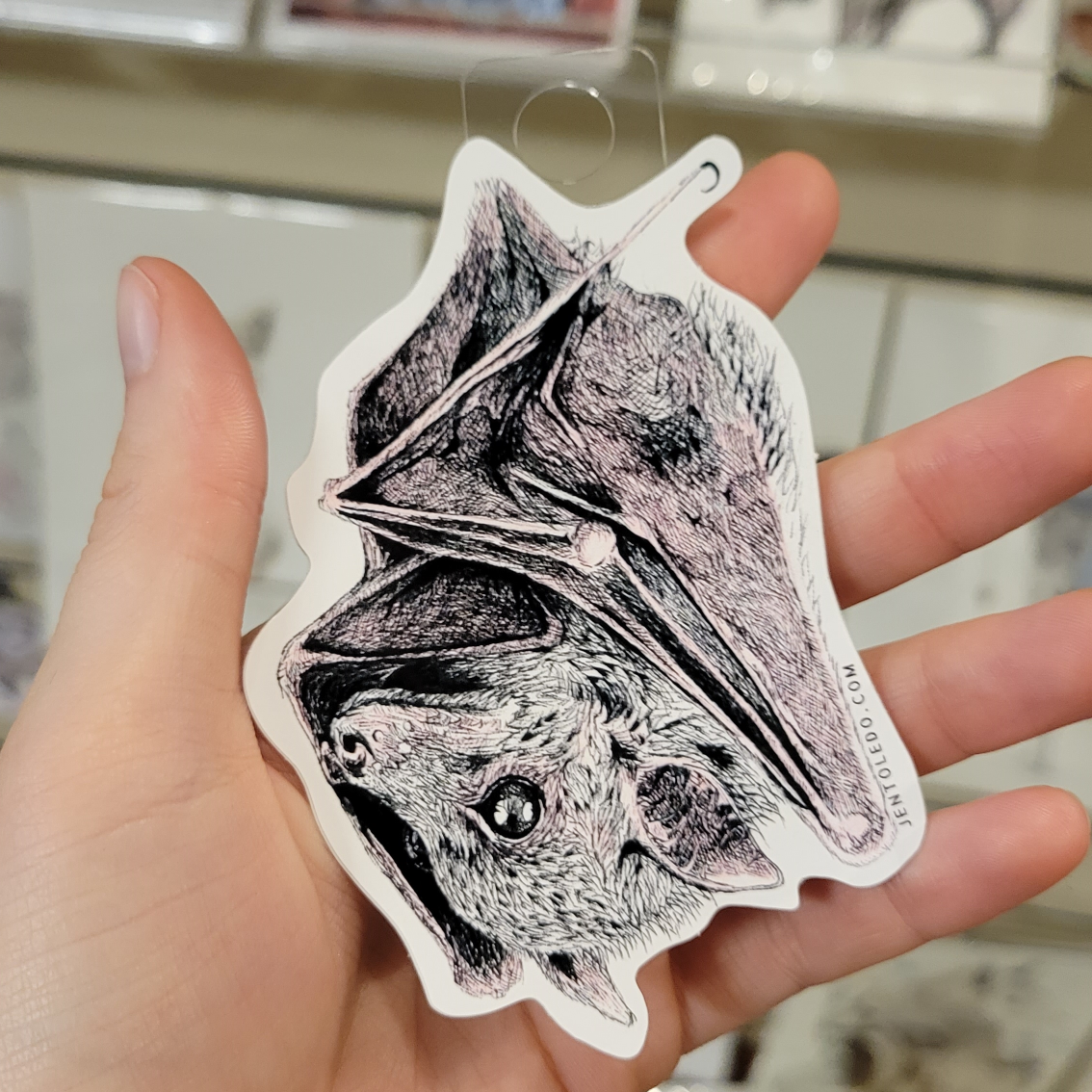 Hand holding bat sticker from artist Jen Toledo