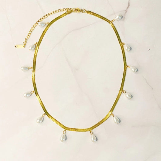 Gold Necklace with pearls on a marble shelf