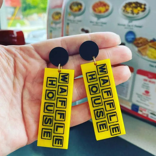 Hand holding Waffle house earrings with menu in the background