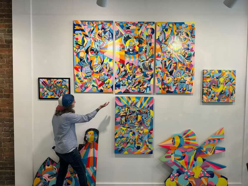 Artist Maxx Feist showcasing their art on a wall in an art gallery