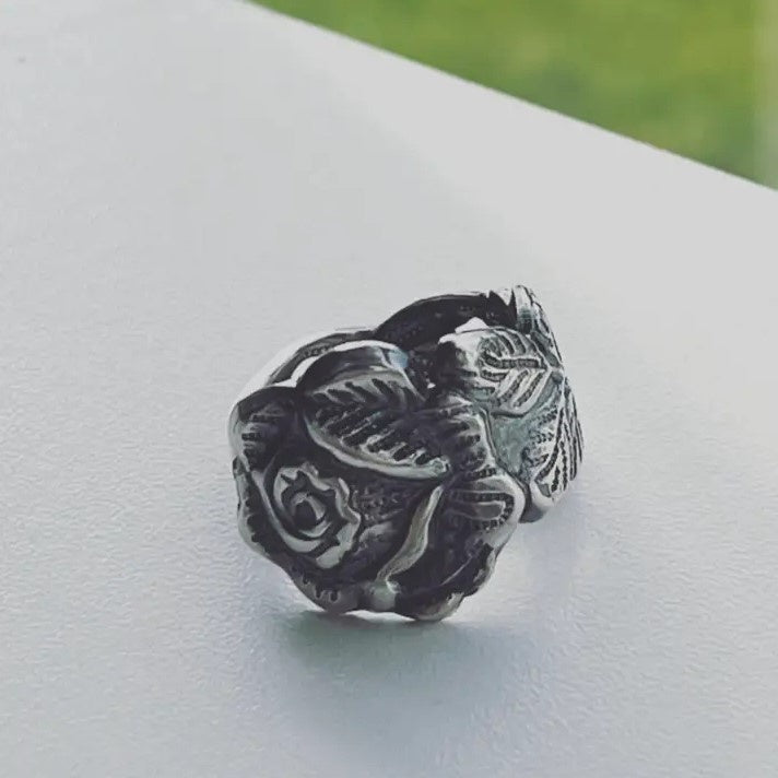 A thick silver ring with a three dimensional engraving of a rose.