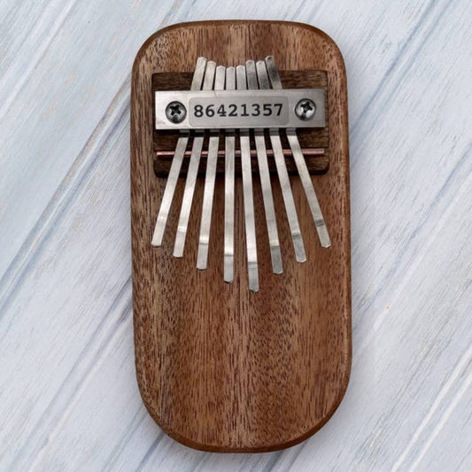 Dark wooden kalimba with metal tines on a light wooden surface