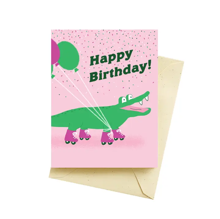 Pink greeting card featuring an illustration of a cartoon alligator in pink roller skates and the words "Happy Birthday!" 