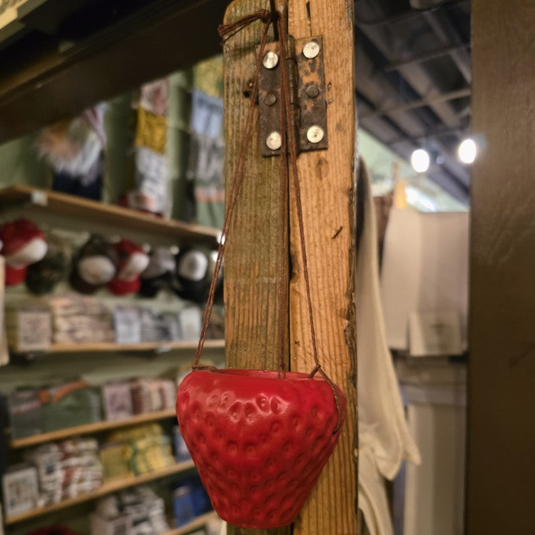 A small hanging planter shaped like a strawberry.