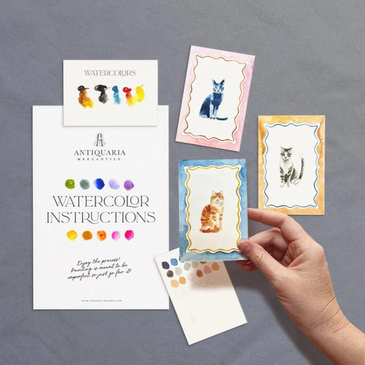 Small watercolor cat paintings next to watercolor painting kit