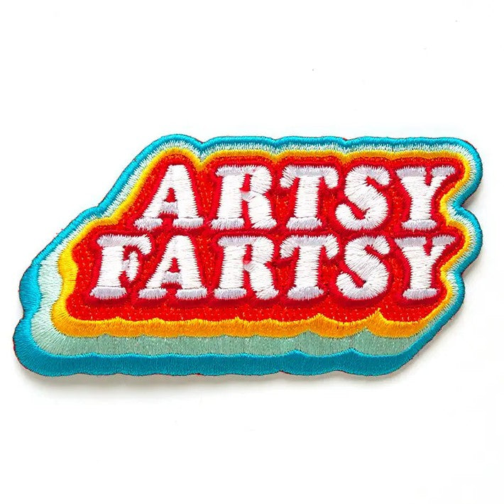 Embroidered fabric patch reading "Artsy Fartsy" on a rainbow background