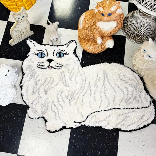 Small rug in the shape of a white Persian cat with blue eyes and a pink tongue lying down.