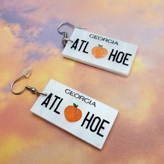 atl license plate earrings that say atl hoe and there is a peach in the middle
