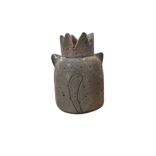 A gray speckled ceramic sculpture with pointy cat ears and a crown on top, and a cat tail drawn on the back