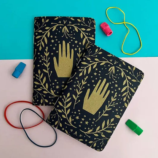 gold hands on dark blue journal with gold leaves and stars