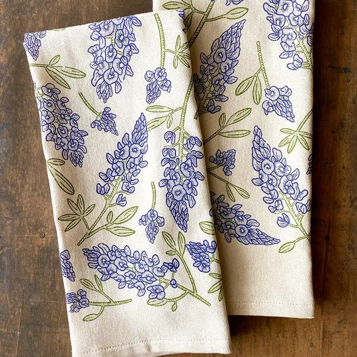 Two cream colored kitchen towels with bluebonnet flower patterns