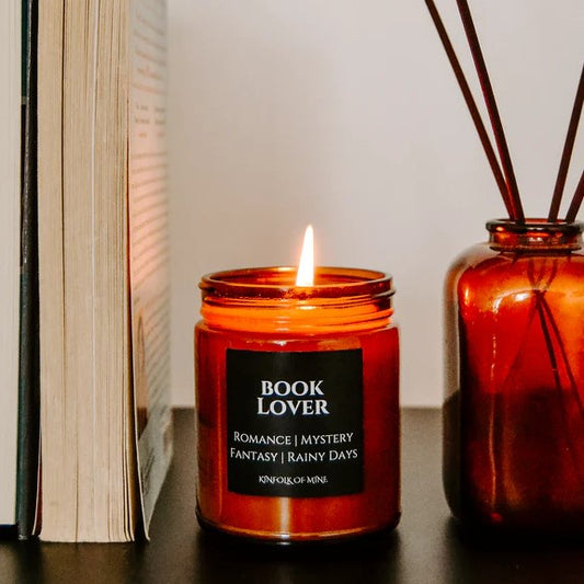 brown candle lit against a bookshelf