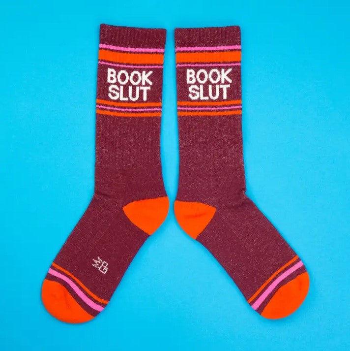 Pair of dark red, orange and pink striped calf socks with the words "Book Slut" printed at the top.