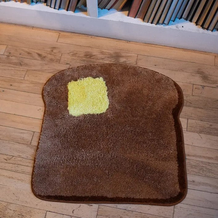 Small rug shaped like a piece of toast with a yellow pat of butter on it.