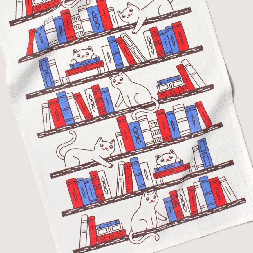 cats laying on a bookshelf design on a tea towel