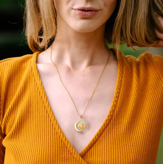 Gold necklace with a pendant shaped like an overlapped sun and crescent moon