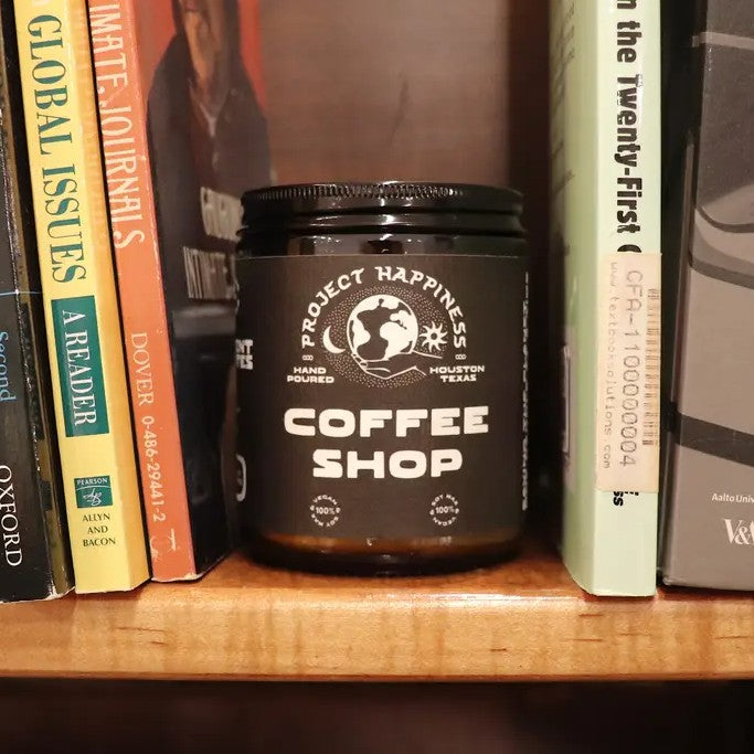 Jar labeled 'Coffee Shop' by 'Project Happiness' on a bookshelf with books around