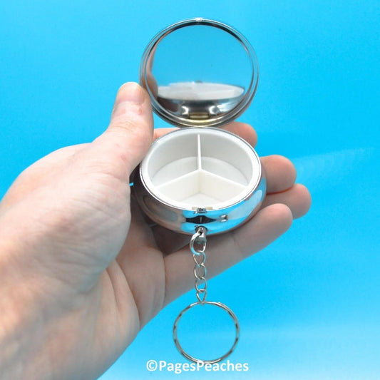 Silver pill organizer with a mirror and keychain 