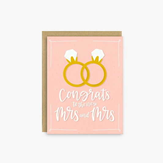 Pink greeting card with two overlapping diamond rings and text that reads "Congrats to the new Mrs. and Mrs."