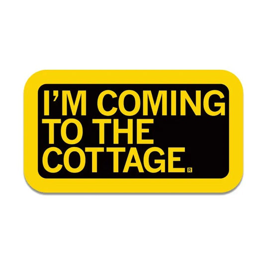A rectangular black sticker with bright yellow text "I'm coming to the cottage."