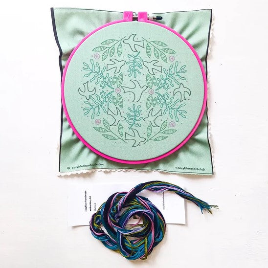 The contents of the embroidery kit including the embroidery hoop with design outline printed on it and thread.