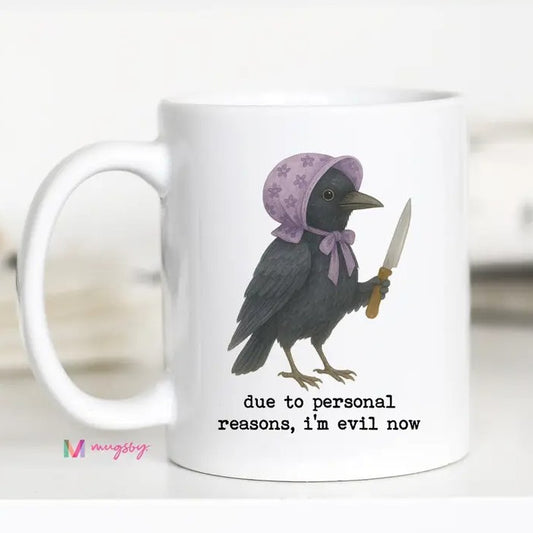 A white ceramic mug featuring a printed illustration of a black raven wearing a lavender bonnet and holding a knife, with the text 'due to personal reasons, i'm evil now' below. 