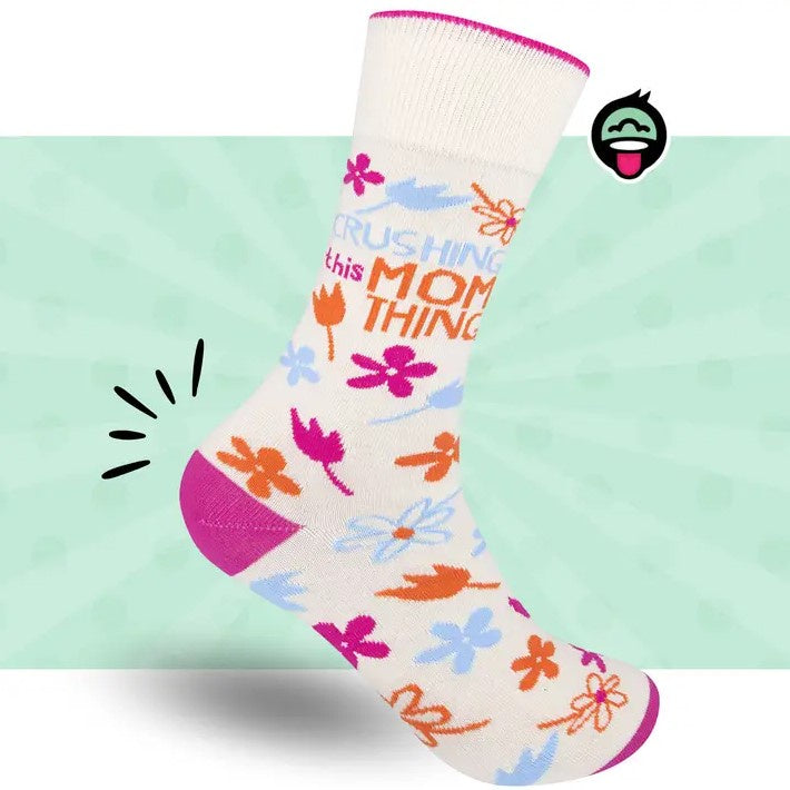 White calf socks decorated with simple orange, blue and hot pink flowers and the words "Crushing this mom thing"