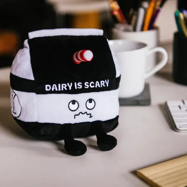 Plush toy shaped like a milk carton with a frowny face and embroidered words that read "dairy is scary"