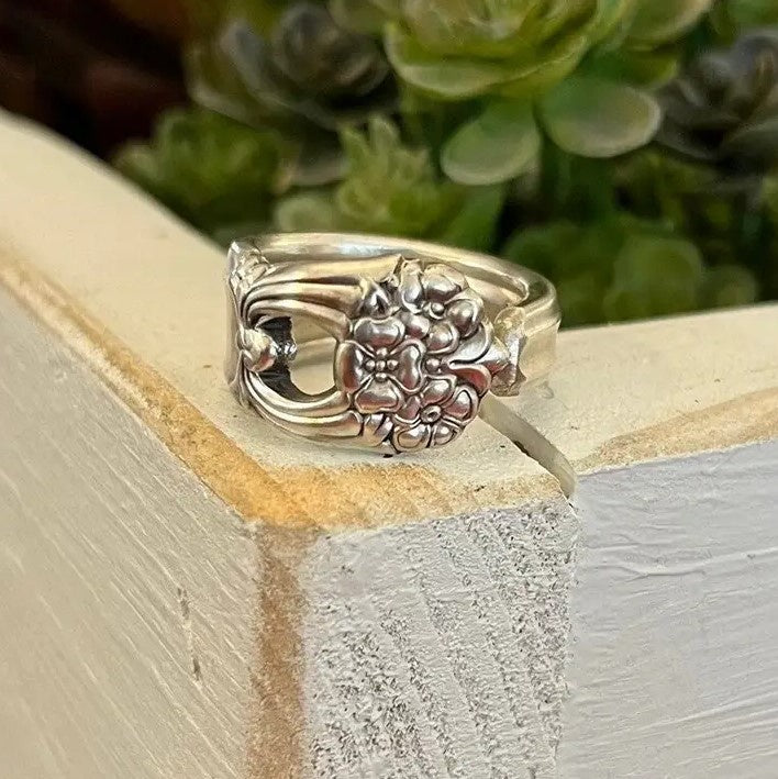 A thick silver ring with a three dimensional bouquet of flowers engraved.