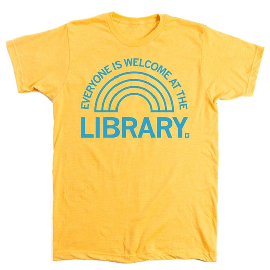 Yellow t-shirt with a light blue rainbow shaped graphic and text that reads "Everyone is welcome at the library"