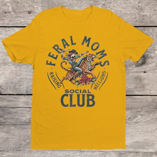 Yellow t-shirt with a graphic of a woman riding a tiger and text "Feral Moms Social Club"