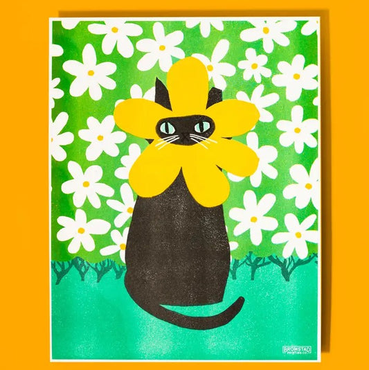 Risograph print of a black cat with a yellow flower around its face in front of a green and white floral background
